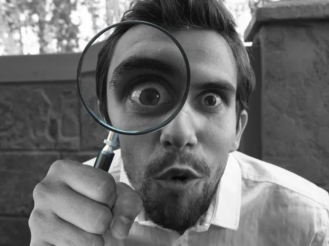 Man looking through magnifying glass